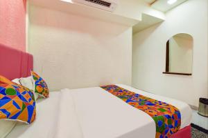 a bedroom with a white bed with colorful pillows at FabHotel Avadh Palace in Ahmedabad