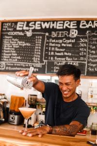 a man is making a drink in a bar at Surf & Party - Hostel Somewhere Else in Canggu