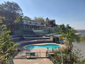 a swimming pool with benches and a building in the background at Hotel O Pratikruti Resort in Pune +8 photos