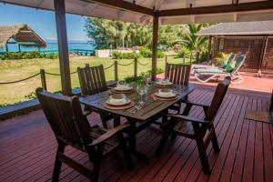 uma mesa de madeira e cadeiras num deque com um guarda-sol em Vai Villas em Avarua