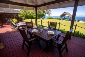 uma mesa de madeira e cadeiras num deque com o oceano em Vai Villas em Avarua