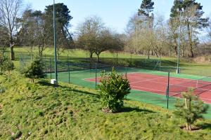 a tennis court on a grassy hill with trees at HAYNE BARN ESTATE - Froggies - Independent Self contained studio on private estate in Postling