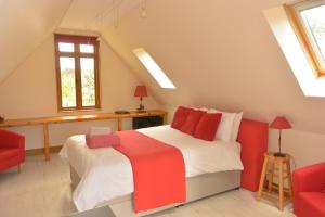 1 dormitorio en el ático con 1 cama y 1 silla roja en HAYNE BARN ESTATE - Froggies - Independent Self contained studio on private estate en Postling