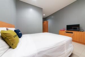 1 dormitorio con cama blanca y almohada amarilla en RedDoorz Plus near Kelapa Dua Kebon Jeruk, en Yakarta