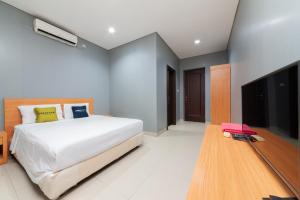 a bedroom with a bed and a flat screen tv at RedDoorz Plus near Kelapa Dua Kebon Jeruk in Jakarta