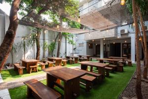 a group of tables and benches in a room with trees at RedDoorz Plus near Kelapa Dua Kebon Jeruk in Jakarta