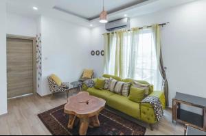 ein Wohnzimmer mit einem grünen Sofa und einem Tisch in der Unterkunft Executive 2 bedroom Apartment At East Legon in Accra