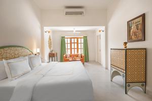 a bedroom with a large white bed and a couch at Gaj Kesri by 7Apple Resorts in Bikaner