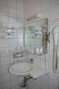 a white bathroom with a sink and a shower at Hôtel sud alsace in Ranspach-le-Bas