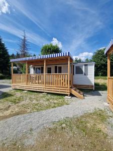 a manufactured home with a deck and a house at Albatross Mobile Homes on Camping Bella Austria in Sankt Peter am Kammersberg
