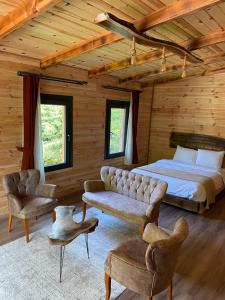 a bedroom with a bed and a couch and chairs at Tepe Dağ Evleri in Çamlıhemşin
