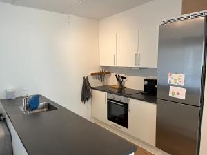 a kitchen with white cabinets and a stainless steel refrigerator at Charming Aalborg Apartment With parking in Aalborg