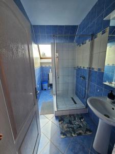 a blue tiled bathroom with a shower and a sink at Fűzfa Apartman in Joseni