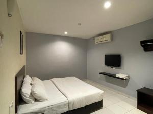 a bedroom with a white bed and a tv at M Three Hotel Seri Manjung in Kampong Batu Tiga