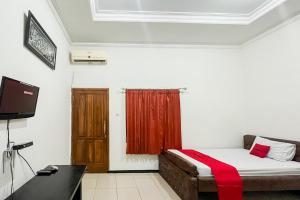 a small room with a bed and a television at RedDoorz Syariah At Santana Stasiun Kepanjen in Malang