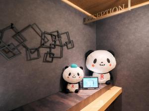 due panda ripieni seduti su uno scaffale con un portatile di Rakuten STAY Tokyo Asakusa Twin Room a Tokyo