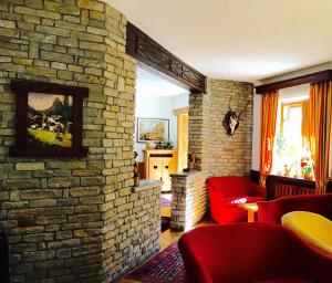 a living room with a brick wall and red chairs at Hotel Dei Camosci in Courmayeur