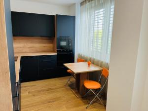 een kleine keuken met een houten tafel en oranje stoelen bij Apartmán Sitka in Trenčín