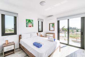 a white bedroom with a large bed and large windows at Villa Elpida THREE by Ezoria Villas in Timi, Paphos in Paphos City