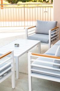 a white coffee table and two chairs on a patio at Villa Elpida THREE by Ezoria Villas in Timi, Paphos in Paphos