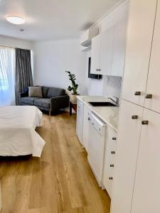 a kitchen with white cabinets and a bed in a room at Resort Queen Studio at Alex Beach Resort in Alexandra Headland