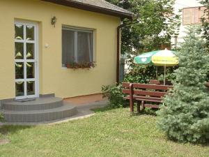 een geel huis met een bank en een paraplu bij Emese Apartman in Hajdúszoboszló