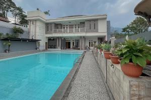a house with a swimming pool and potted plants at RedDoorz Resort Syariah At Rancakalong Sumedang in Sumedang