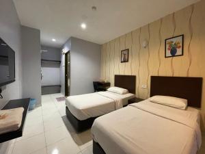a hotel room with two beds and a flat screen tv at M Three Hotel by SECOMS in Kampong Batu Tiga