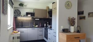 a kitchen with white cabinets and a clock on the wall at Haus Adrian in Wald am Arlberg