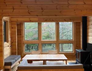 uma sala de estar com uma mesa e uma grande janela em 【moi】山中湖 新築フィンランドログハウス 大自然の中でBBQ可 em Yamanakako