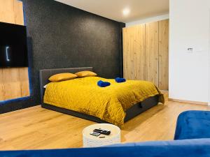 1 dormitorio con cama amarilla y almohadas azules en Apartmán Sitka, en Trenčín