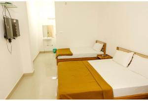 deux lits dans une chambre avec une télévision au mur dans l'établissement sevens residency, à Sultan Bathery 13 autres photos