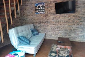 - un salon avec un canapé et un mur en briques dans l'établissement Bushveld Bliss, à Marloth Park