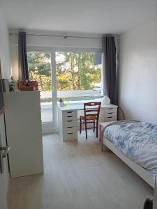 a bedroom with a bed and a desk and a window at Joli appartement bien situé pour les JO in Les Essarts-le-Roi