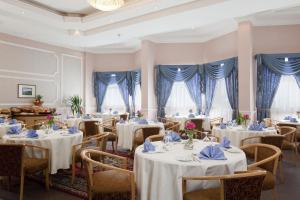 un restaurante con mesas y sillas blancas y cortinas azules en Gloria Inn Najran, en Najrán