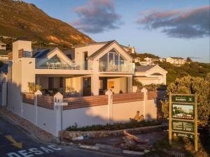 Simonʼs Town的住宿－Boulders Beach Villa，前面有标志的大白色房子