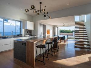 una cocina con una gran isla con taburetes de bar en Boulders Beach Villa, en Simonʼs Town