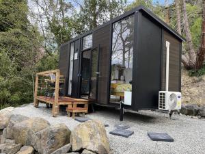 a black tiny house sitting on top of rocks at Cosy Dell in Herbert
