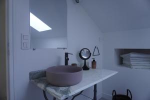 ein Badezimmer mit einem Waschbecken auf einer Marmortheke in der Unterkunft Le Domaine du Moulin 28 in Bailleau-lʼÉvêque