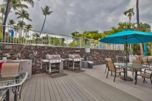 una terraza con mesas, sillas y sombrilla en Alii Villas Cozy 1BR Unit Near DT (5 Guests), en Kailua-Kona