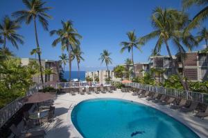a swimming pool with chairs and palm trees and the ocean at Alii Villas Cozy 1BR Unit Near DT (5 Guests) in Kailua-Kona