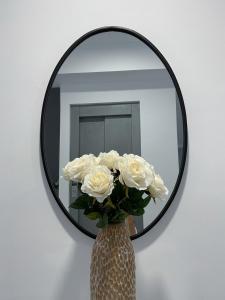 un jarrón de rosas blancas delante de un espejo en Apartamentos Lusitania Parking Gratis bajo disponibilidad en Mérida