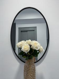 a vase of white roses in front of a mirror at Apartamentos Lusitania Parking Gratis bajo disponibilidad in Merida