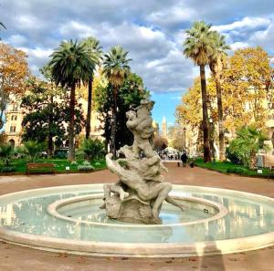 una estatua en una fuente en un parque con palmeras en Esquiline Suites, en Roma