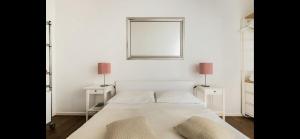 a white bedroom with a bed with two lamps and a mirror at Esquiline Suites in Rome