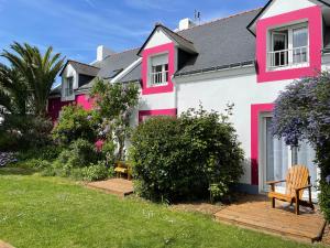 une maison rose et blanche avec un banc dans la cour dans l'établissement Hotel Aux Tamaris, à Sauzon