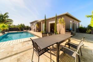 un patio avec une table et des chaises à côté d'une piscine dans l'établissement Villa avec piscine vue mer et montagne, en pleine nature, à Saint-Joseph 88 autres photos