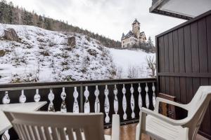 a balcony with two chairs and a house in the snow at 2203 Modernes Studio mit Balkon in Vulpera