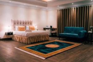 a bedroom with a bed and a chair and a rug at Falettis Grand Bahawalpur in Bahawalpur