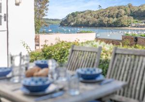a table with bowls and plates on it with a view of the water at Popigale Cottage in Helford
